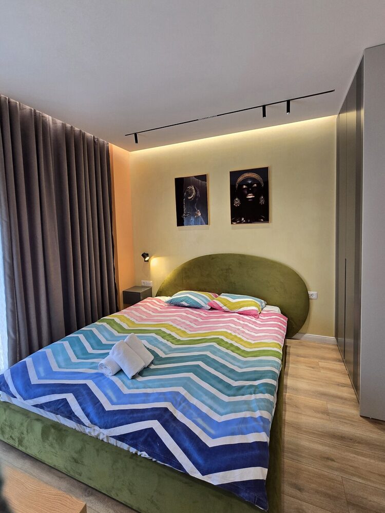Bed with colorful linens and modern artwork above the headboard