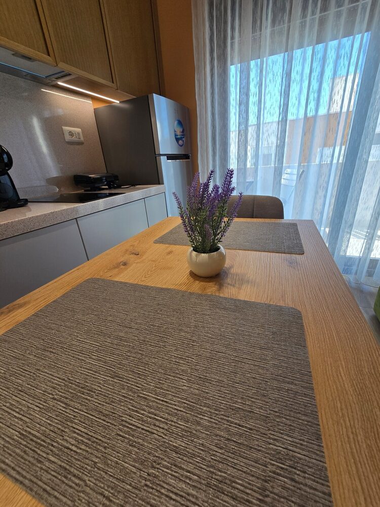 Dining table with kitchenette and balcony door in the background