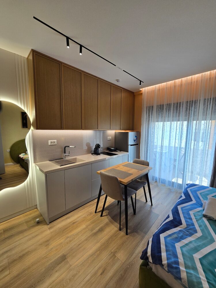 Open-plan studio with kitchenette, dining table, and sea-view balcony
