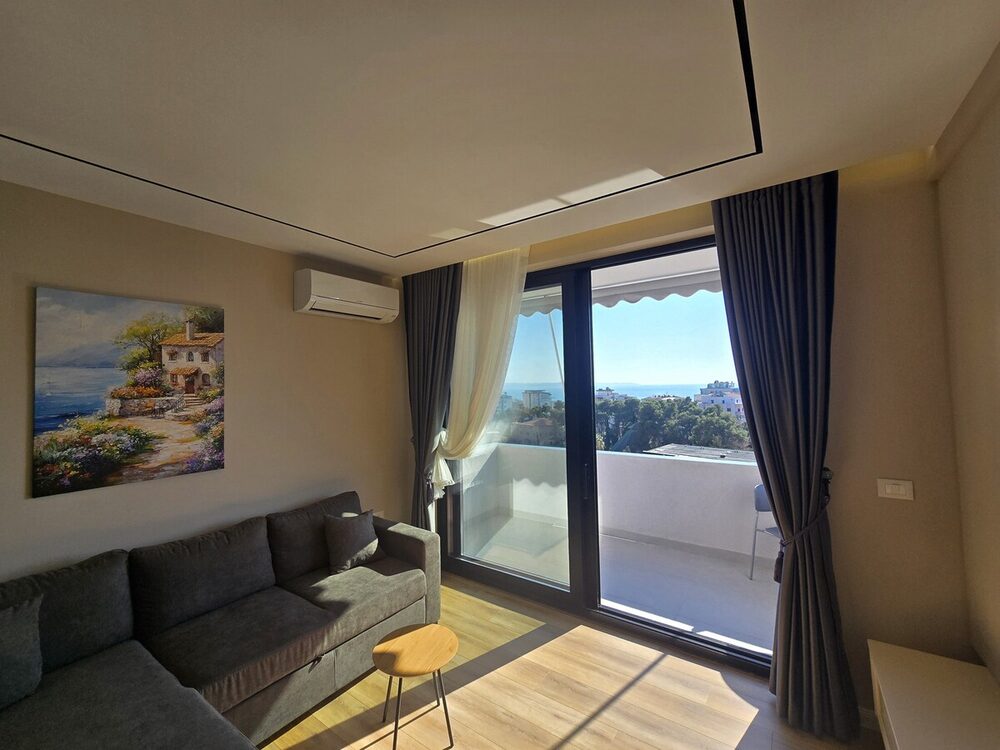 Bright living room opening onto a private balcony with a sea view