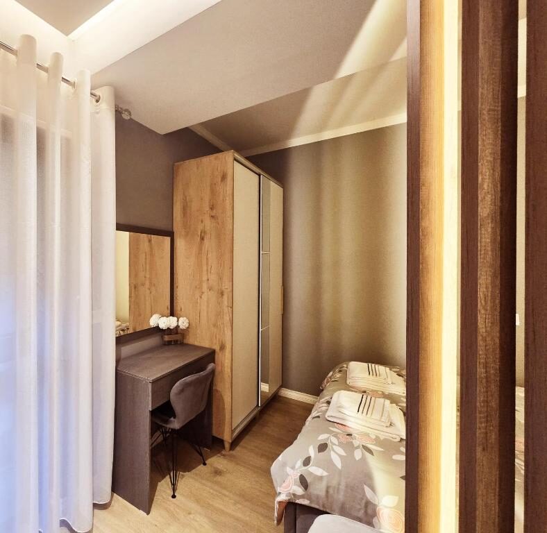Bedroom with a desk beside the curtained window